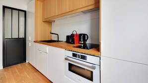 A compact kitchen with white cabinets, a wooden countertop, a Bosch oven, and a black coffee maker. - Charming studio A/C - 2P - Le Marais (Paris)