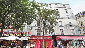 A café with outdoor seating, red umbrellas, and a banner reading "La Baguette du Relais." - Charming studio A/C - 2P - Le Marais (Paris)