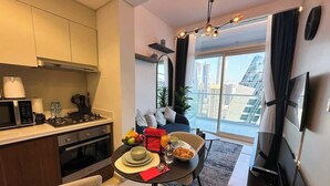 A modern living space with a kitchen, dining area, and a large window with a city view.