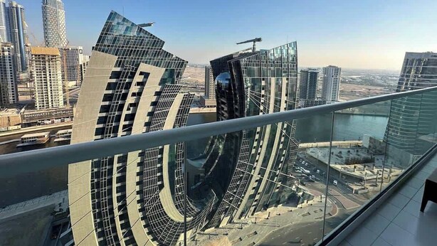 A high-rise building with a curved glass facade and a view of the surrounding cityscape.
