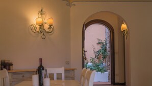 Zona pranzo con tavolo apparecchiato per quattro, una bottiglia di vino, candele e una pianta in vaso.