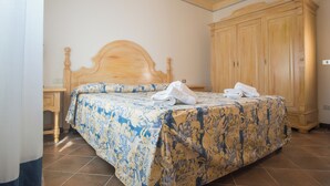 Una camera da letto con un letto di legno, un armadio capiente e un pavimento piastrellato.