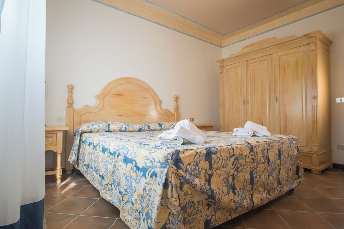 Une chambre à coucher avec un lit en bois, une grande armoire et un sol carrelé.