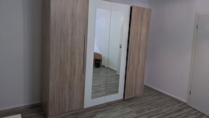 A room with a large wardrobe featuring a mirrored door and wooden panels. - NestOaseWHV Zimmer zw.City und Südstrand (Wilhelmshaven)