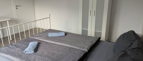 A bedroom with a bed, a wardrobe, and a small table.