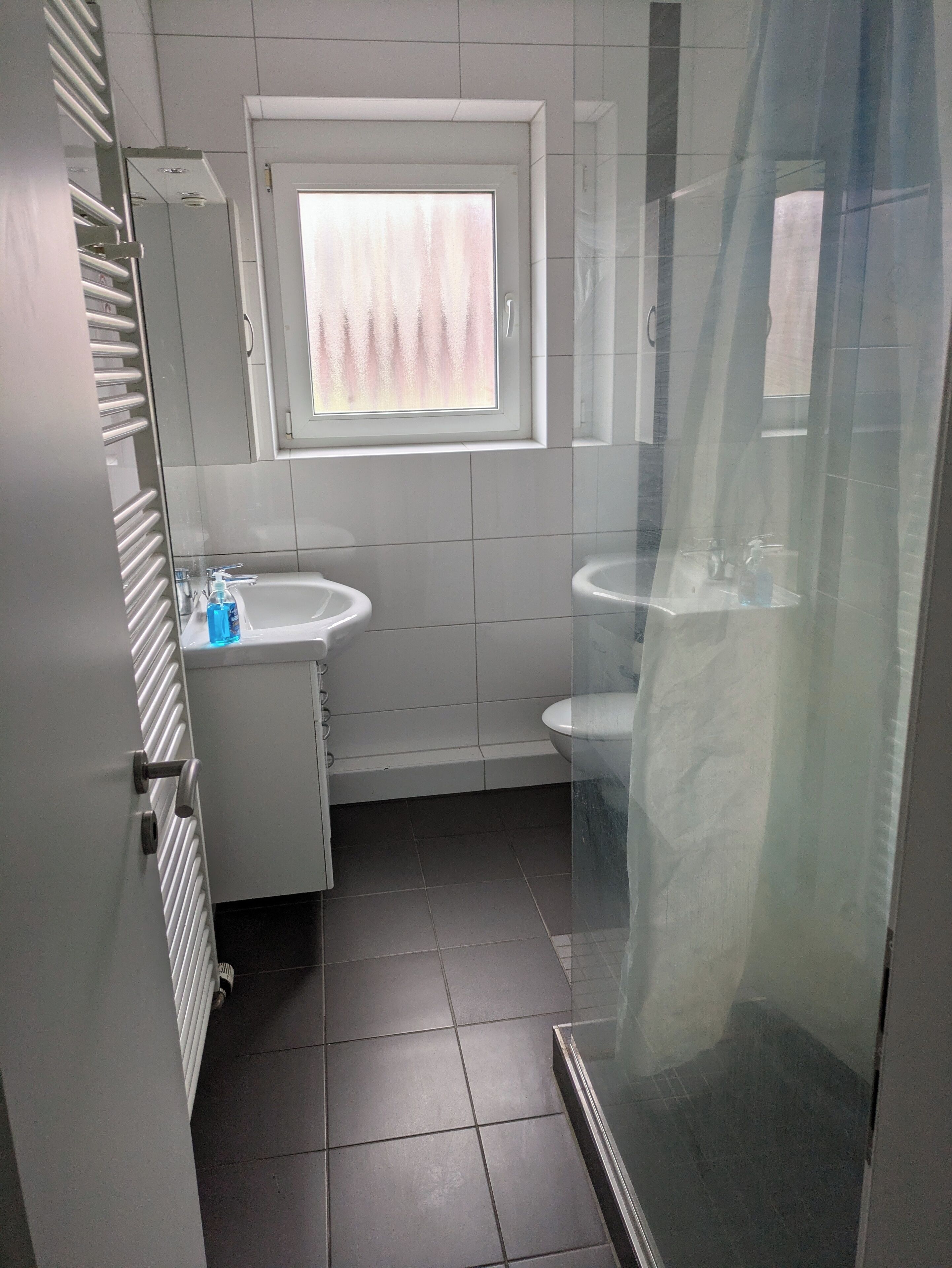 Et moderne badeværelse med et vindue, to håndvaske, toilet og bruser.