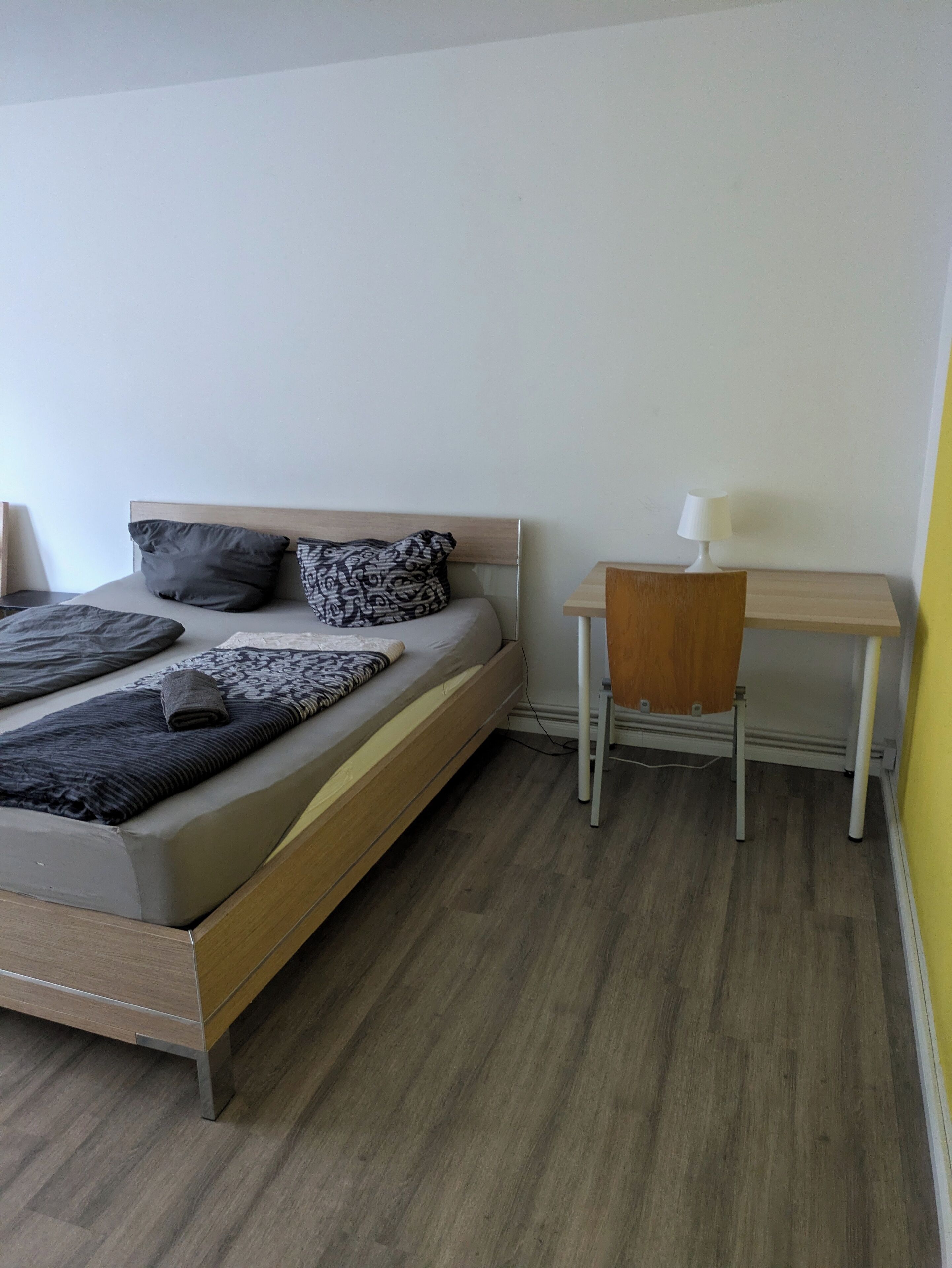 A bedroom with a bed, a desk, and a chair.