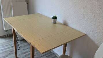 Una habitación con una mesa de madera, una silla blanca y una pequeña planta en maceta.