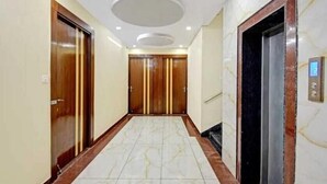 A hallway with marble flooring, wooden doors, and an elevator. - The Sawera- Haridwar (Haridwar)