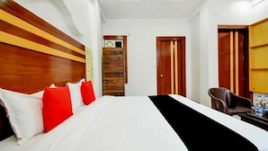 A hotel room with a large bed, wooden headboard, and a desk with a chair. - The Sawera- Haridwar (Haridwar)