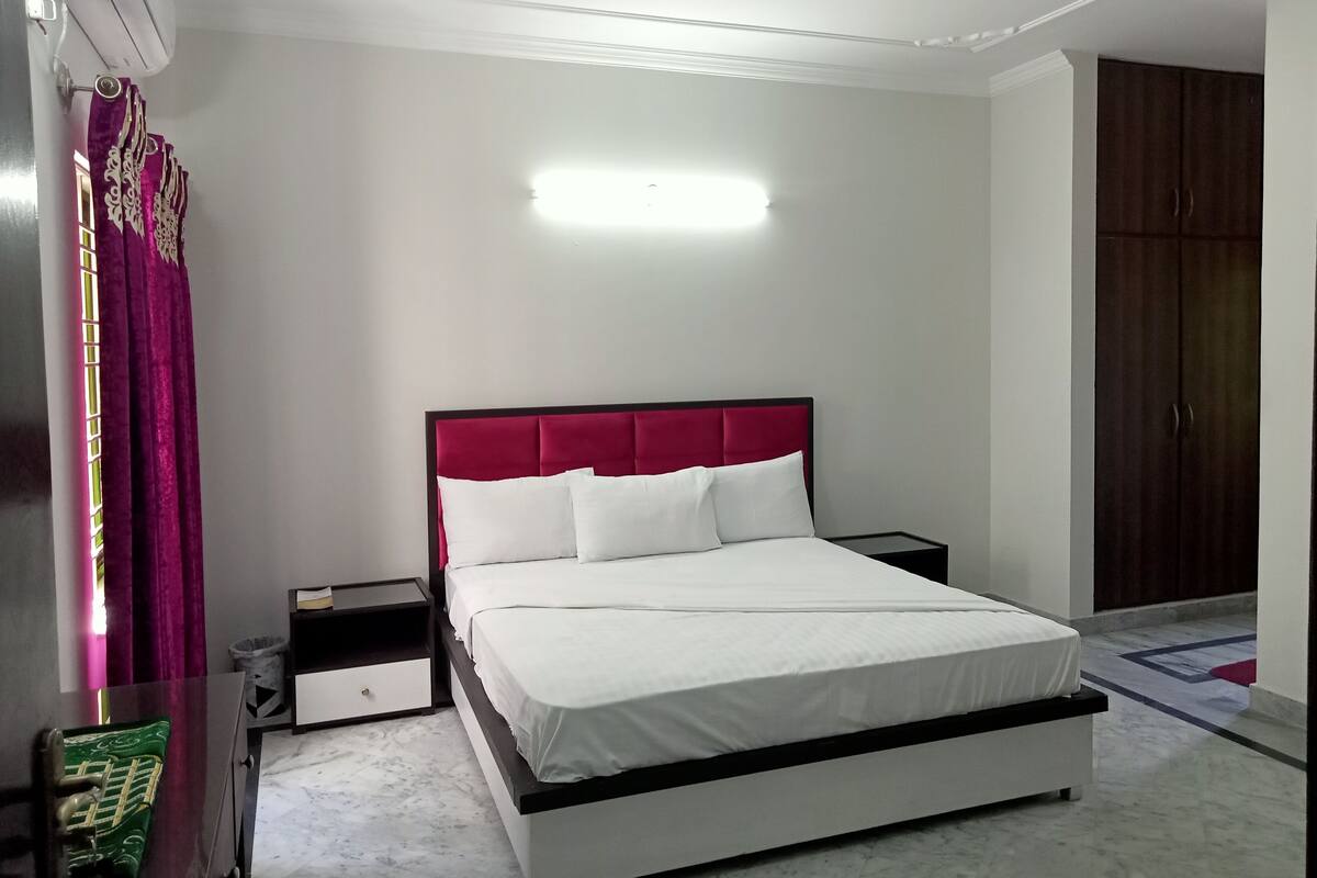 Ein Schlafzimmer mit Bett, Nachttisch, Kleiderschrank und Deckenventilator.