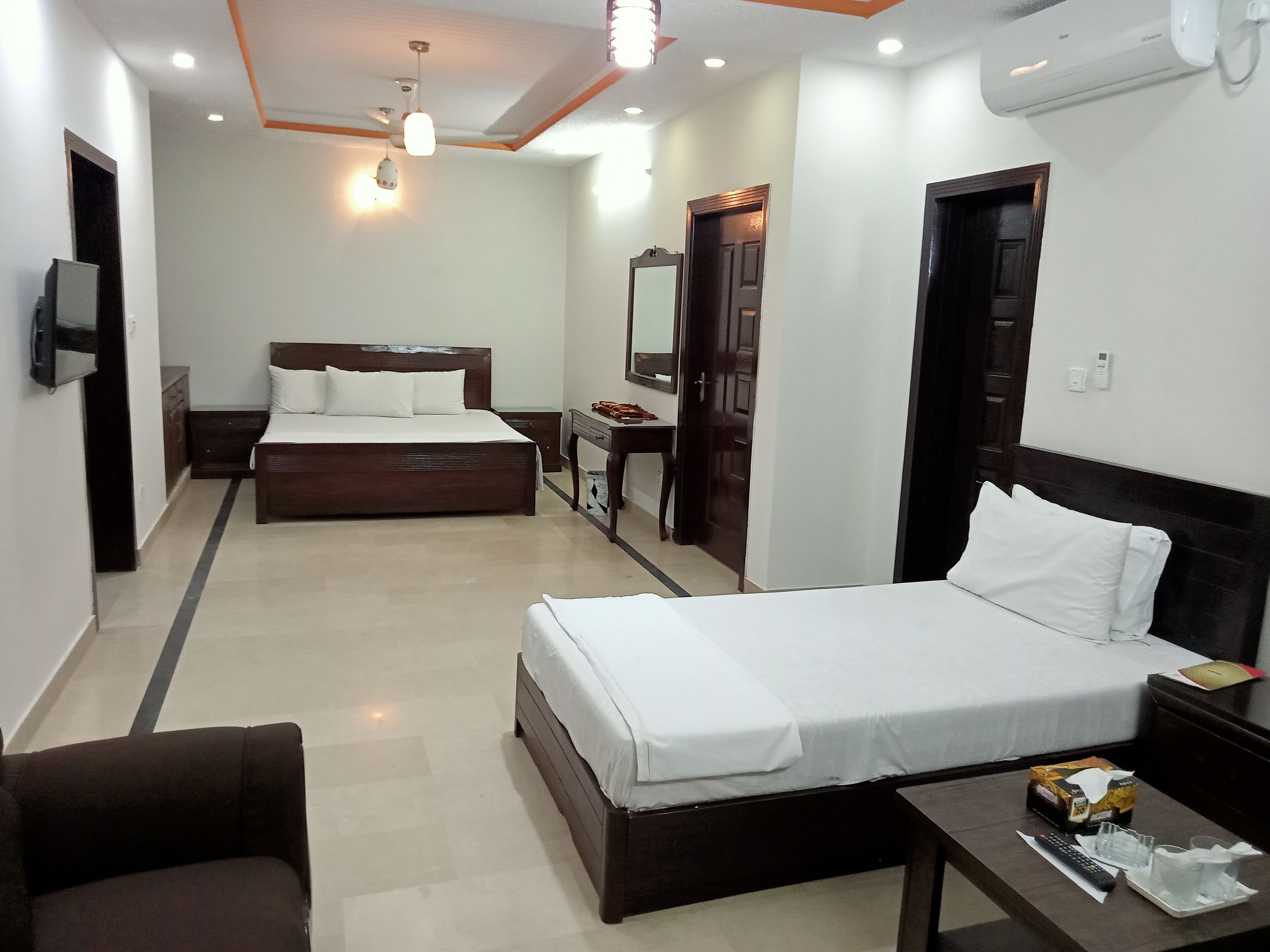 A hotel room with two beds, a desk, a chair, a TV, and a wardrobe.