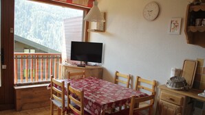 A dining area with a table set for four, a television, and a view of a forested mountain. - Joran JR7 Sunny & View 4 Pers (Chatel)