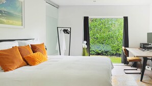 A modern hotel room with a large bed, a desk with a computer, and a view of greenery through the window. - Lanaken Retreat Pool Jacuzzi and Sauna (Lanaken)