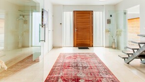 A modern hotel lobby with a wooden door, glass walls, and a red patterned rug. - Lanaken Retreat Pool Jacuzzi and Sauna (Lanaken)