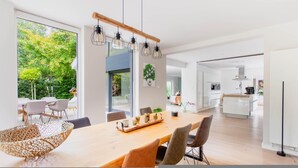 A modern dining area with a wooden table, chairs, and pendant lights. - Lanaken Retreat Pool Jacuzzi and Sauna (Lanaken)