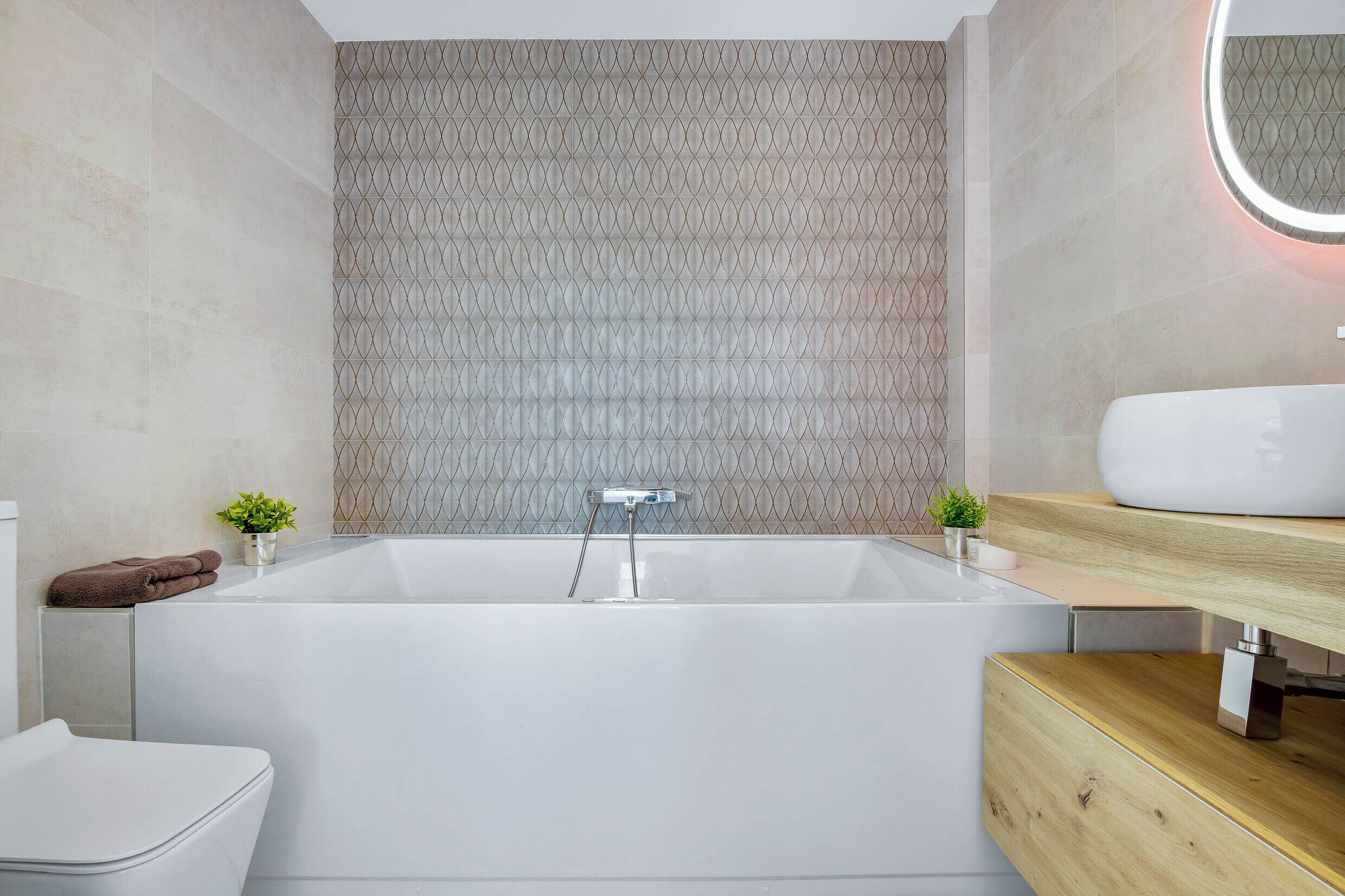 Een moderne badkamer met een vrijstaand bad, een houten wastafelmeubel en een spiegel aan de muur.