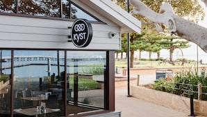 Een restaurant met een bord waarop 'KYST' staat en een brug op de achtergrond.
