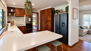 A modern kitchen with a central island, wooden cabinetry, a built-in oven, and a black refrigerator.