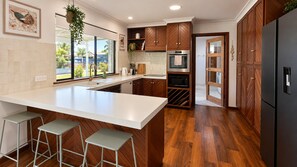A modern kitchen with a large island, wooden cabinets, and a view of the outdoors.
