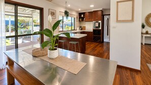 A modern kitchen with wooden cabinets, a central island, and a view of the outdoors. - Broadwater Break: Stylish Coastal Retreat for Families (Broadwater)
