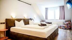 A bedroom with a large bed, a small table, a sofa, and a TV mounted on the wall. - Comfortable and versatile room -perfect for relaxation, work and exchange (Winterberg)