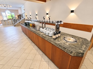 A buffet setup with a marble countertop, wooden cabinets, and wall-mounted light fixtures.