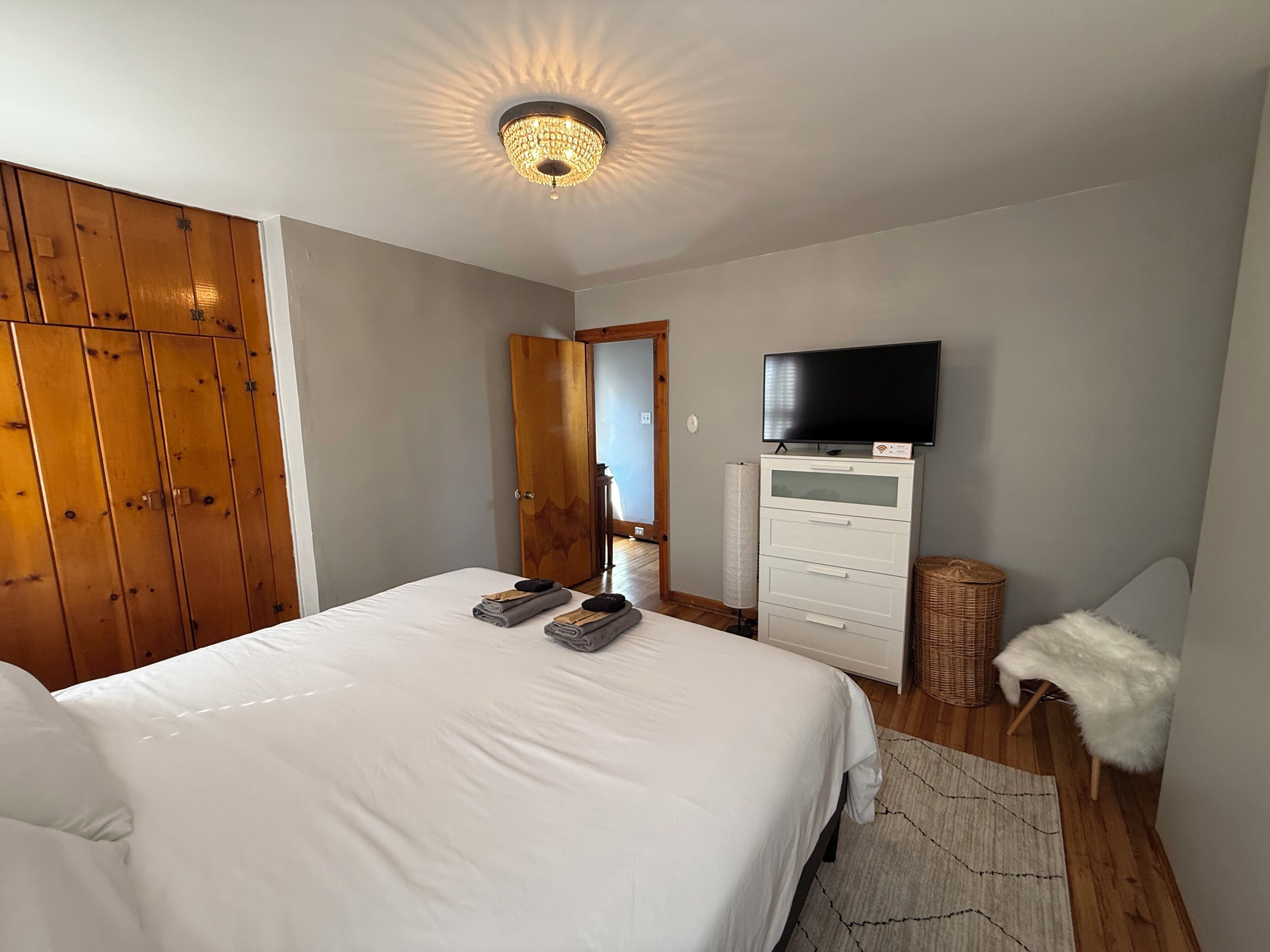 Un dormitorio con cama, televisión, armario y espejo.