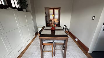 A dining area with a wooden table and chairs, a white cabinet, and a plant.
