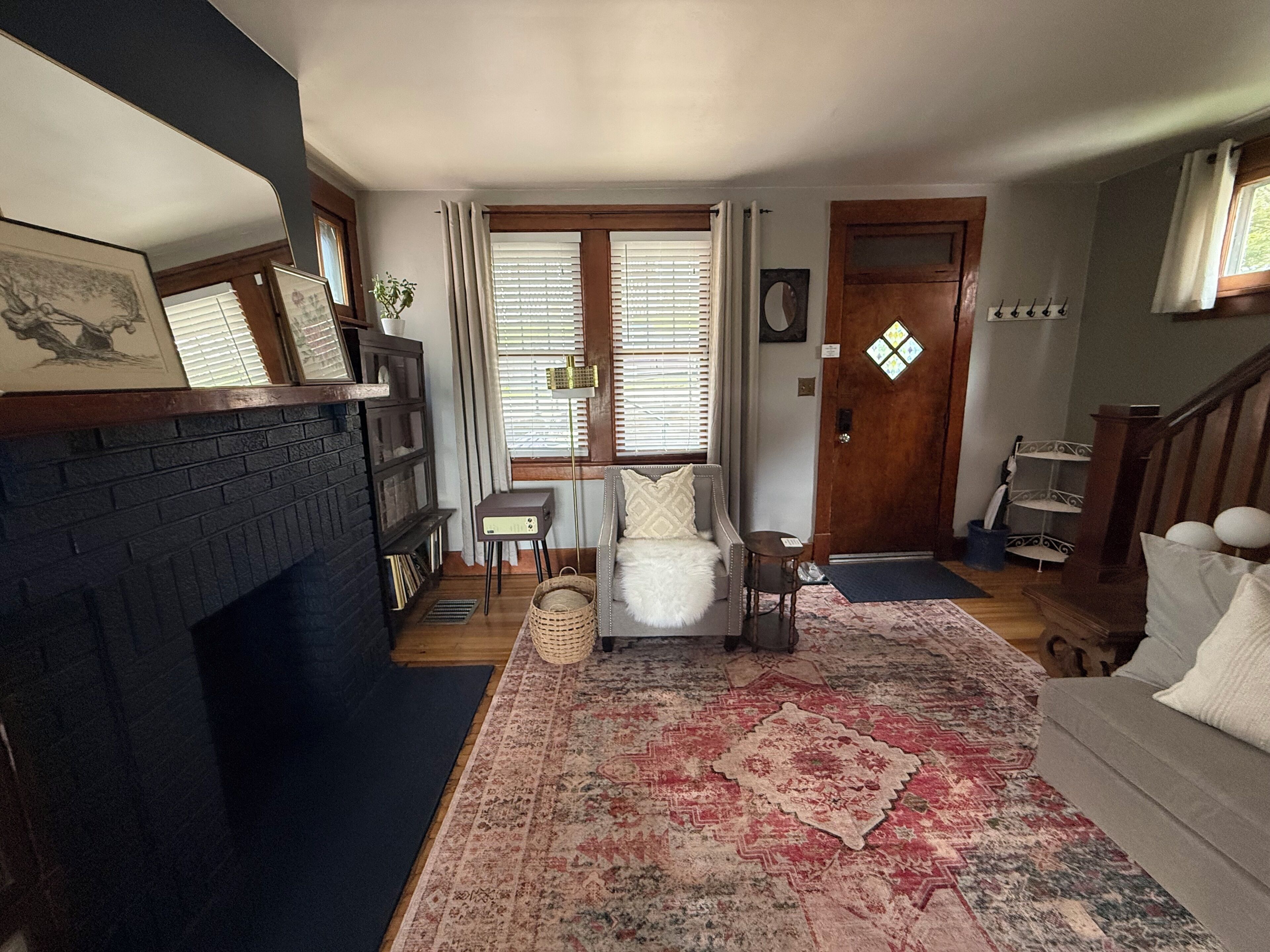A living room with a fireplace, a sofa, a rug, and a staircase.