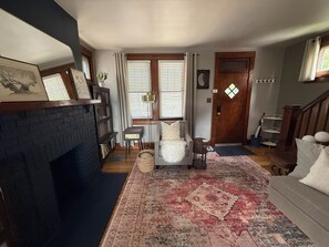 Una sala de estar con chimenea, un sofá, una alfombra y una escalera.