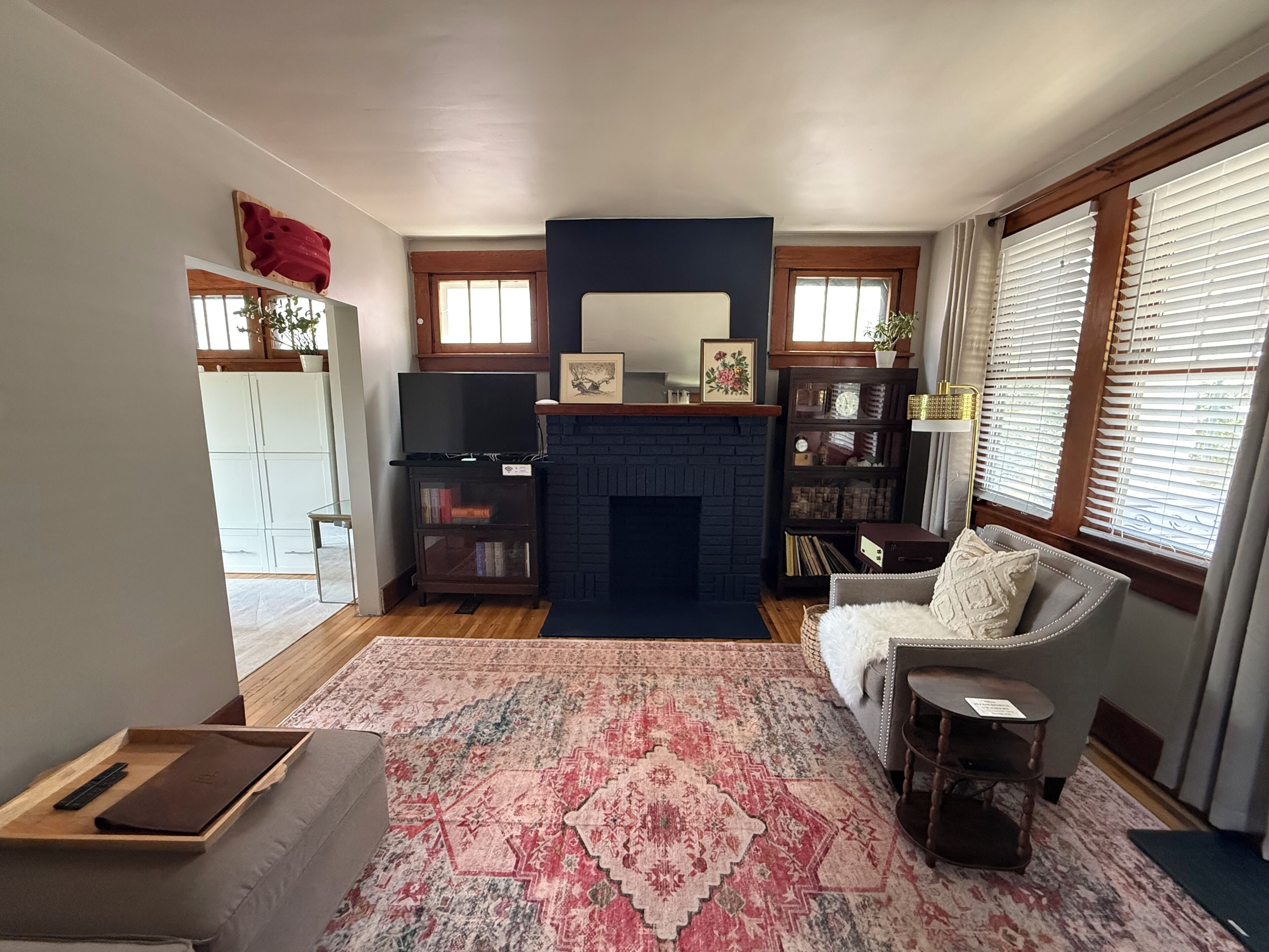 A living room with a fireplace, a bookshelf, a television, and a patterned rug.