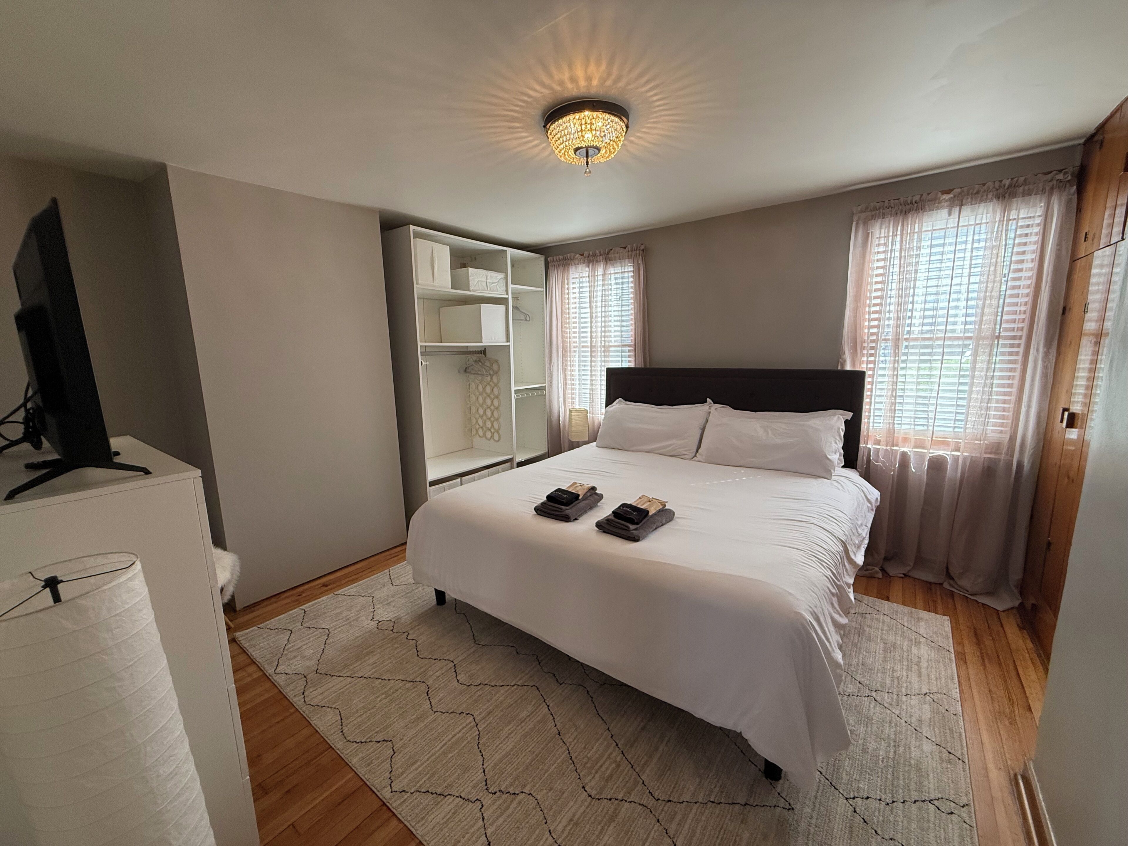 A bedroom with a bed, a TV, a wardrobe, and a ceiling light.