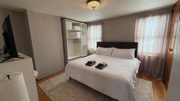 A bedroom with a bed, a TV, a wardrobe, and a ceiling light.