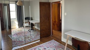 A room with a mirrored wardrobe, a desk, a chair, a patterned rug, and a hanging light fixture. - Pittsburgh city views close to all, cozy & bright 1BR - King + Dedicated Office (Pittsburgh)