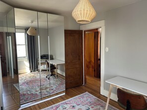 A room with a mirrored wardrobe, a desk, a chair, a patterned rug, and a hanging light fixture. - Pittsburgh city views close to all, cozy & bright 1BR - King + Dedicated Office (Pittsburgh)