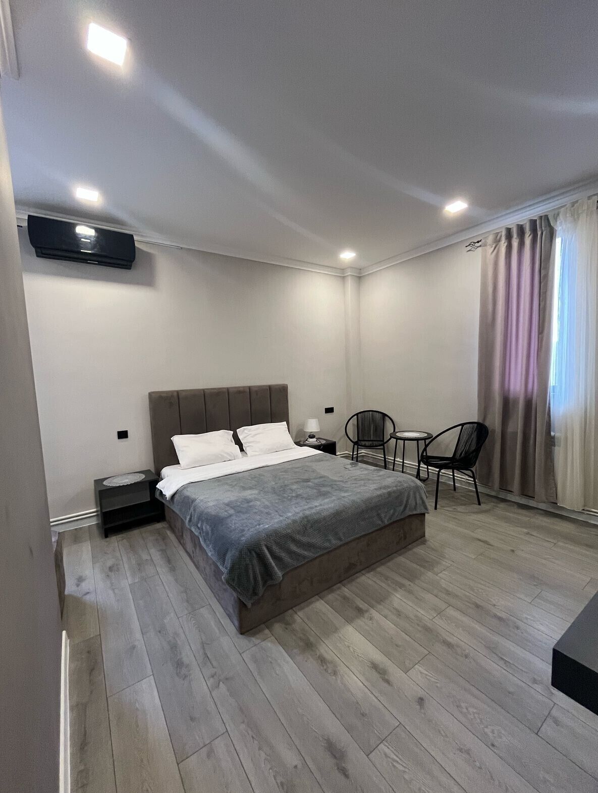 Un dormitorio con cama, mesitas de noche, una silla y una pequeña mesa.