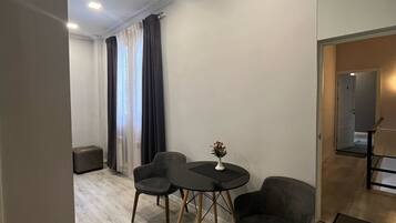 A modern room with a round table, two chairs, a bench, and a small table with a vase.
