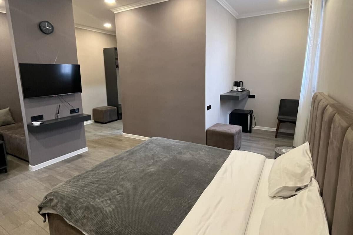 A modern hotel room with a large bed, a flat-screen TV, a desk, and a seating area.