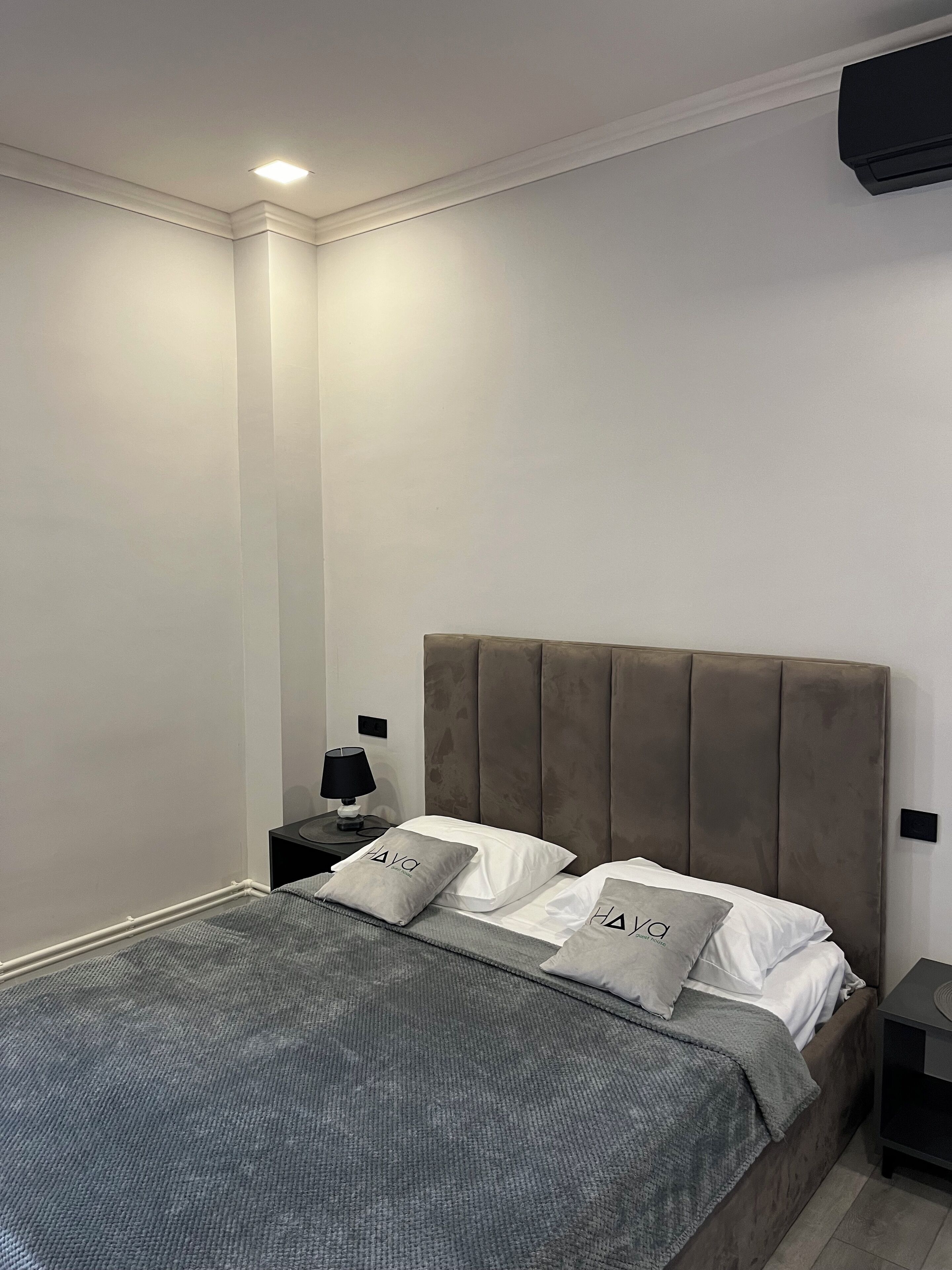 A modern bedroom with a bed, nightstands, and a wall-mounted TV.