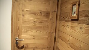 Una porta in legno con maniglia metallica e una piccola cornice con un'immagine appesa alla parete adiacente.