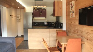 Una cucina moderna con mobili in legno, un'isola centrale e un'area pranzo con sedie arancioni.