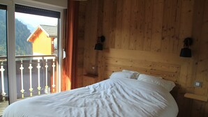 A bedroom with a large bed, wooden walls, and a balcony with a view of mountains. - Veronica Vr51 Nature & Mountain 6 Pers (Chatel)