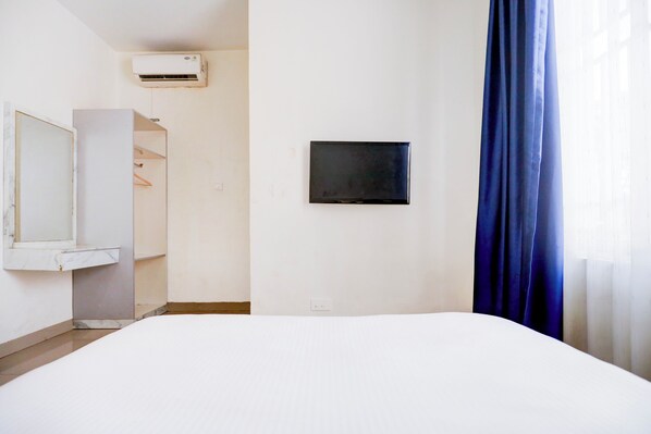 Une chambre d’hôtel équipée d’un lit, d’un téléviseur fixé au mur, d’une armoire et d’un appareil de climatisation.
