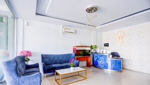 A modern hotel reception area with a blue sofa, a marble coffee table, and a reception desk.