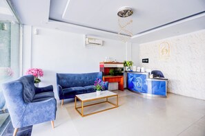 A modern hotel reception area with a blue sofa, a marble coffee table, and a reception desk. - Collection O Waterfront City Near Rsud Embung Fatimah formerly ZUDO Hotel (Batam)