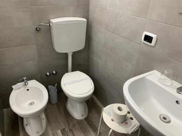 A bathroom with a toilet, bidet, and sink.