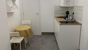 A compact kitchen with a sink, countertop, and a small table with chairs. - Deluxe Room – ALH Hotel Digitale (Taranto)