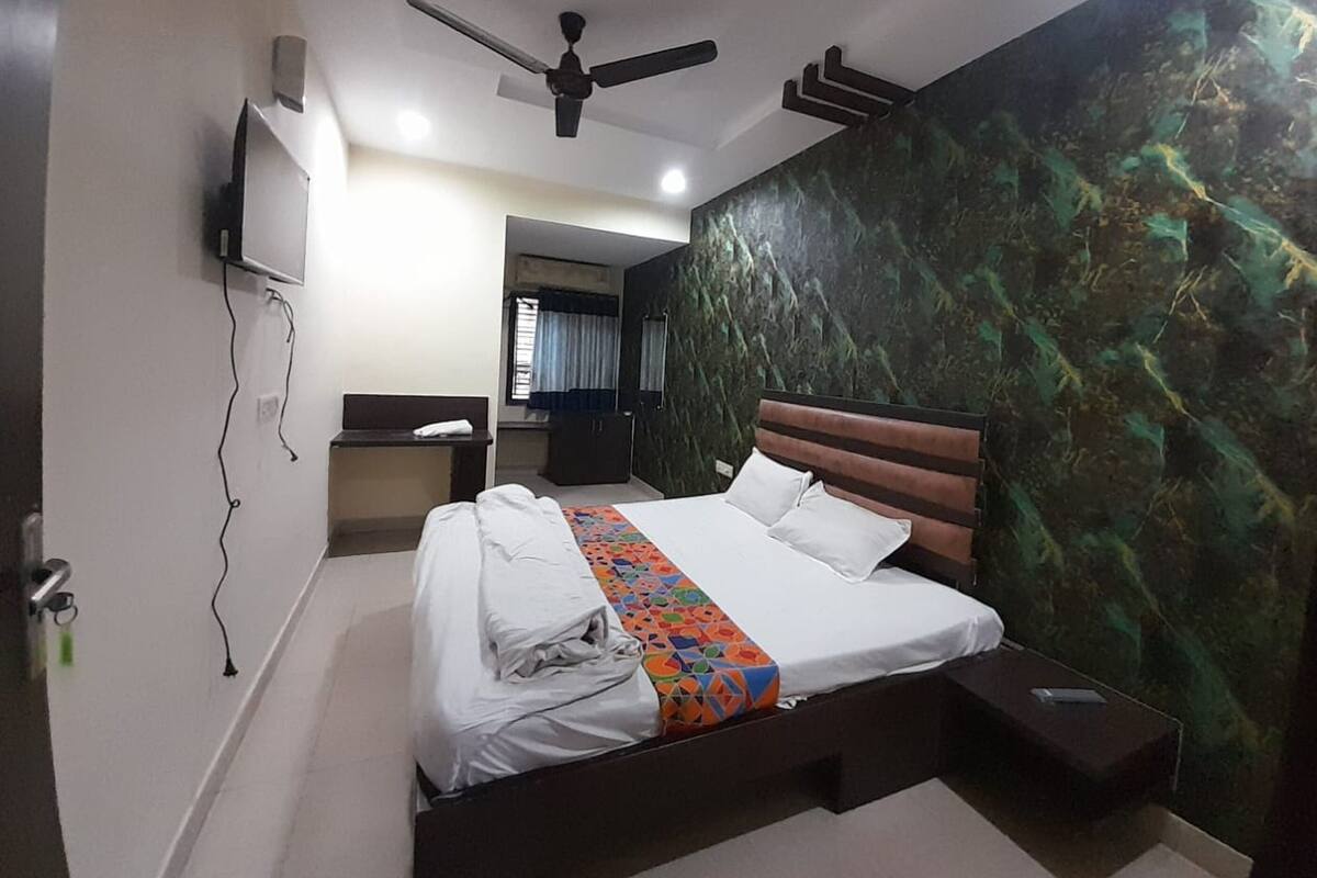 A bedroom with a bed, a desk, a wardrobe, and a ceiling fan.