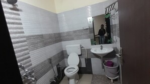 A small bathroom with a toilet, sink, and shower. - Hotel Mezbaan  (Raipur)